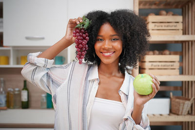 Portrait of smiling young woman standing against wall