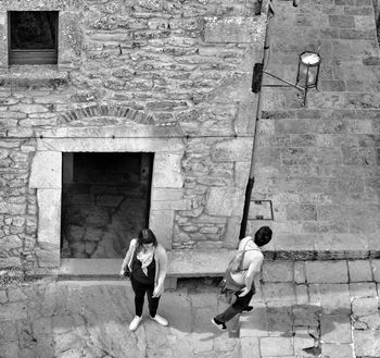 High angle view of two people walking along stone wall