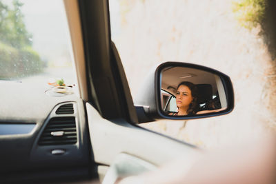 Close-up of woman reflection in side-view mirror