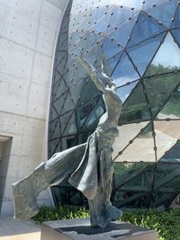 Low angle view of statue by building against sky