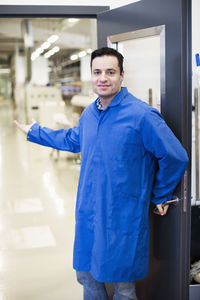 Portrait of mature male electrician welcoming while standing at doorway