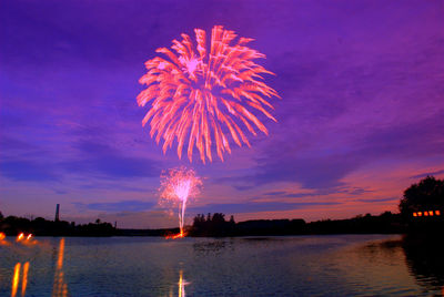 Firework display over sea against sky at night