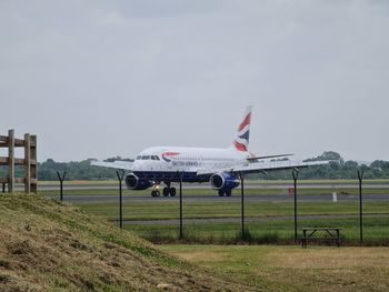 Airplane on airport runway against sky