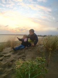 Father and son on shore against sky