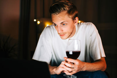 Side view of a young man drinking glass