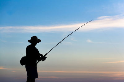 Silhouette man fishing against sky during sunset
