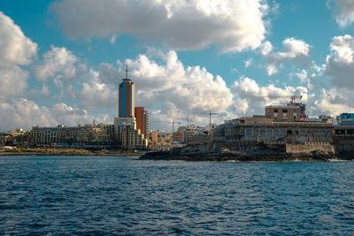 Sea by buildings against sky in city