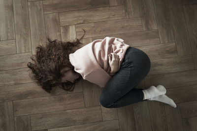 Rear view of woman sitting on hardwood floor