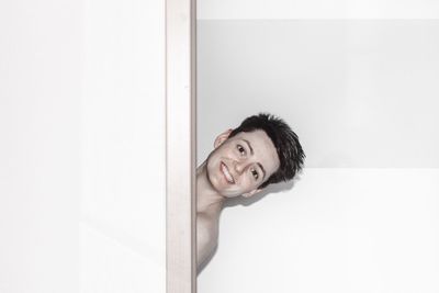 Portrait of smiling young man against white wall