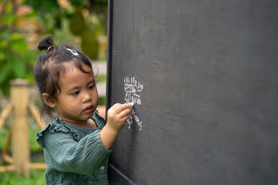 Portrait of cute girl writing alphabet on blackboard