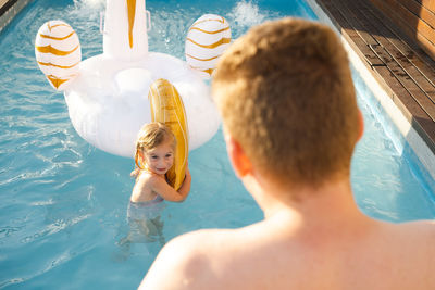 High angle view of man and kid swimming playing in pool