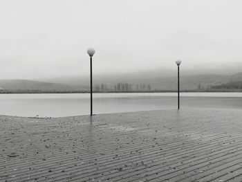 Street light by lake against sky