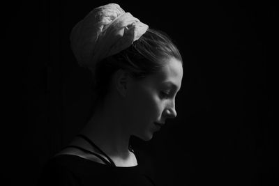 Close-up of young woman against black background