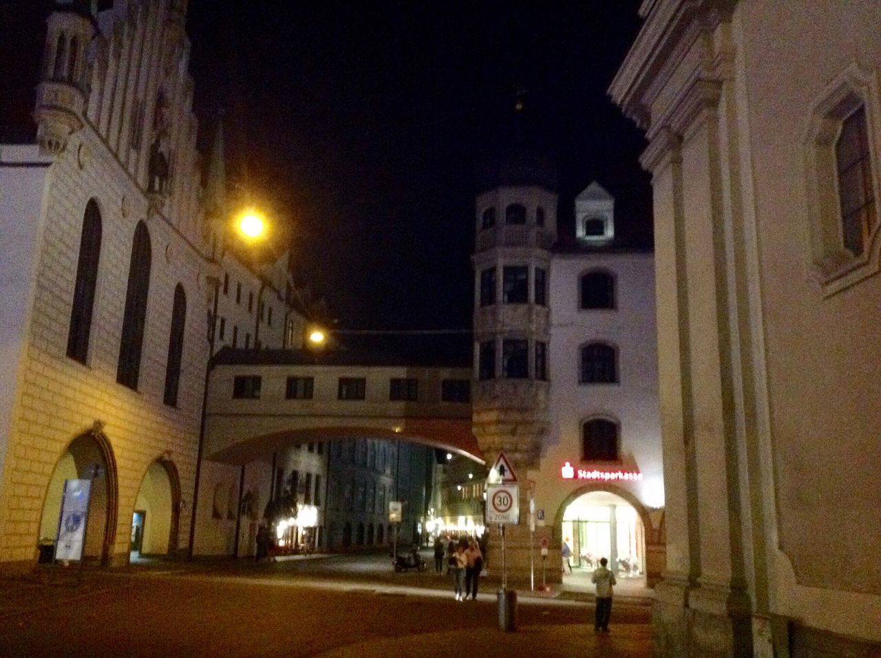 architecture, illuminated, building exterior, night, built structure, street light, city, lighting equipment, road, low angle view, street, arch, city life, outdoors, old town, facade, dark, sky, footpath, in front of, medieval