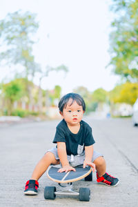 Portrait of boy sitting on skateboard