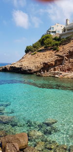 Scenic view of rocks by sea against sky