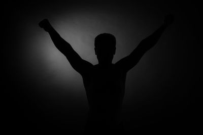 Rear view of silhouette man standing against black background
