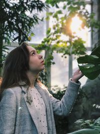 Young woman looking away against trees