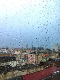 Raindrops on window against sky
