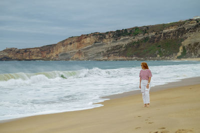 Woman standing at beach against sky