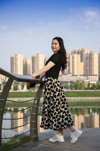 Portrait of smiling young woman standing against sky