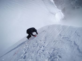 Man climbing snow covered mountain