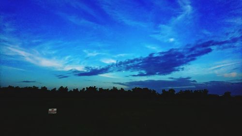 Silhouette trees against blue sky at night