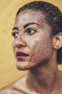 Close-up of thoughtful mid adult woman with glitter on face