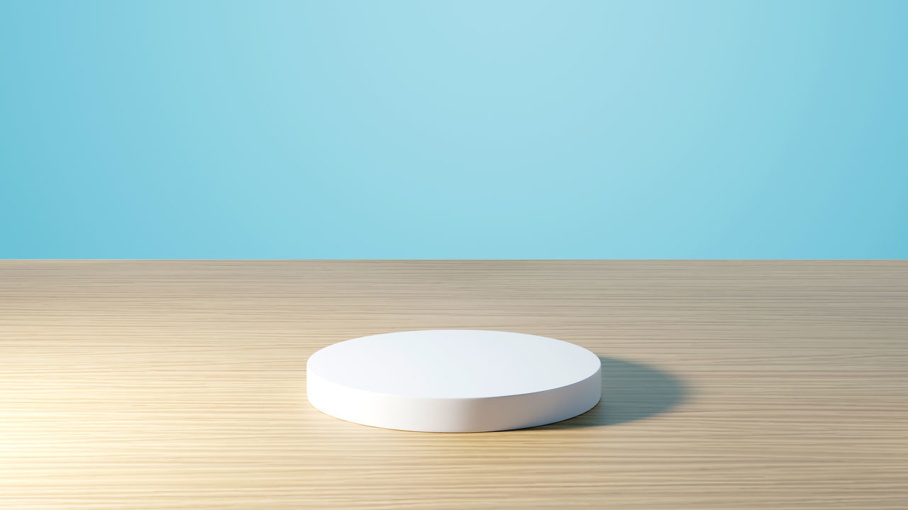 HIGH ANGLE VIEW OF WHITE TABLE AGAINST BLUE WALL ON WOODEN FLOOR