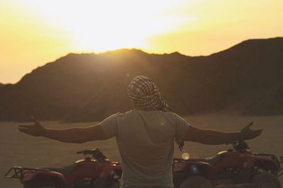 Rear view of woman riding motorcycle on landscape against sky