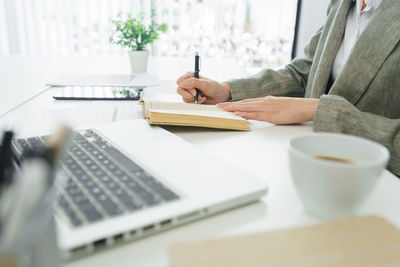 Midsection of woman using laptop on table