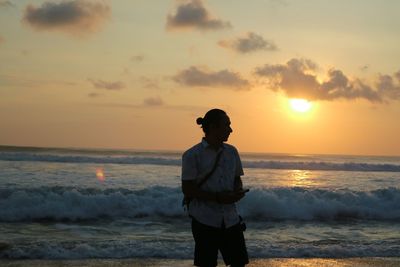 Man standing on beach against sky during sunset