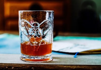 Close-up of drinking glass with carved angel on table