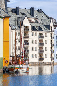 Houses by river against buildings in city