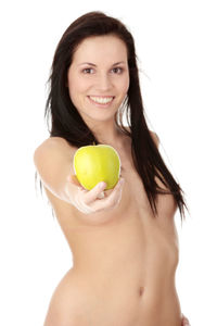 Portrait of young woman holding apple against white background