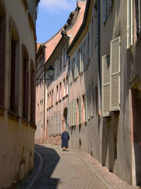 Rear view of man walking on street amidst buildings in city