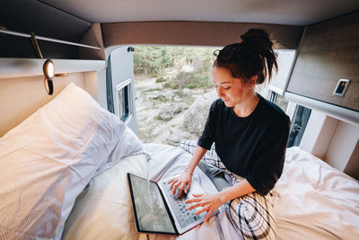 Young woman using laptop in camper