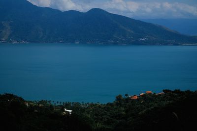 Scenic view of sea and mountains against blue sky