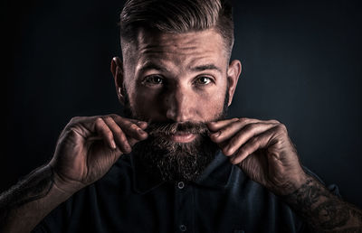 Close-up portrait of man with hand against black background