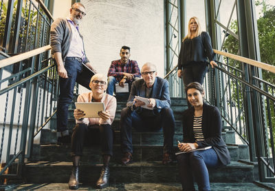 Portrait of confident multi-ethnic business people on stairway in creative office