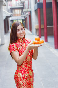 Midsection of woman holding orange while standing outdoors