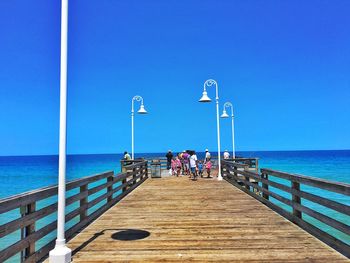 People on sea against clear blue sky