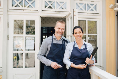 Male and female restaurant owners standing outdoors
