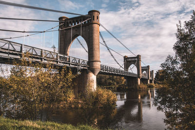 Low angle view of bridge over river against sky