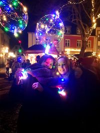 Portrait of woman with illuminated lights in city at night