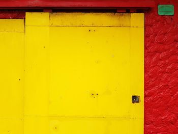 Full frame shot of yellow wall with closed door