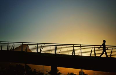 Low angle view of silhouette man standing on footbridge
