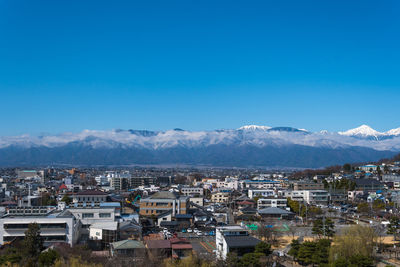 High angle view of houses and mountains against clear blue sky