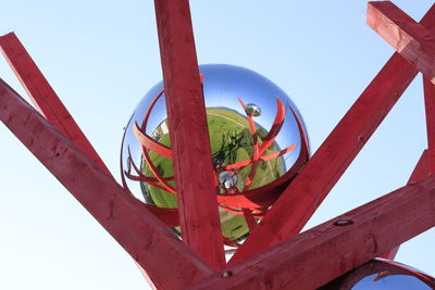 Low angle view of rusty wheel against clear blue sky