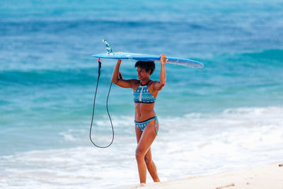 Woman with surfboard wading in sea